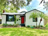 Charming single-story home featuring a bright red door, bay window, and well-maintained front yard with young palm trees at 204 E Harvard St, Orlando, FL 32804