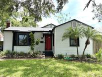 Charming single-story home with a red door, well-maintained lawn, and complemented by lush landscaping at 204 E Harvard St, Orlando, FL 32804