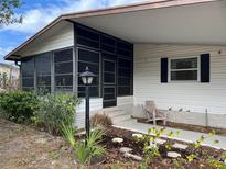 Charming home exterior with a screened-in porch, adorned with beautiful landscaping and a cozy outdoor seating area at 222 Palmer Park Ln, Davenport, FL 33897