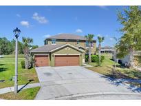 Two-story home featuring a three-car garage, landscaped yard, and traditional architectural details at 3523 Yacht Club Ct, Kissimmee, FL 34746