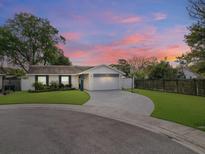 Charming one-story home with a well-manicured lawn and a circular driveway on a cul-de-sac, captured at dusk at 7924 Coot St, Orlando, FL 32822