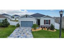 Charming single-Gathering home with a blue garage door, stone accents, and decorative driveway at 9158 Elsa Ct, Davenport, FL 33897