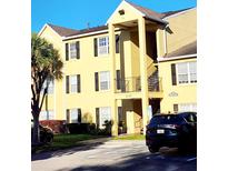 Bright yellow building exterior with black shutters, balcony, and parking at 2047 Dixie Belle Dr # 2047 T, Orlando, FL 32812