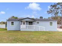 Charming single story home with a white porch railing, blue siding and green front lawn at 3139 Morning Light Way, Kissimmee, FL 34744