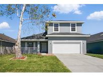 Two-story home featuring a two-car garage, manicured lawn, and covered porch at 4411 Great Harbor Ln, Kissimmee, FL 34746