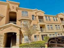 Attractive condominium building with balconies, manicured landscaping, and ample parking under a clear blue sky at 619 Terrace Ridge Cir # 619, Davenport, FL 33896