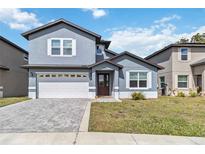 Charming two-story home features a brick paved driveway, well-kept lawn, and attached two-car garage at 6592 Taxiway Cir, Orlando, FL 32822