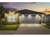Charming home featuring a two-car garage, stone accents, solar panels and a well-manicured lawn at 669 Persian Dr, Haines City, FL 33844