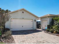 Home featuring a 2-car garage with brick-paved driveway and well-maintained landscaping at 759 Villa Park Rd, Poinciana, FL 34759