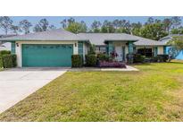 Inviting single-story home featuring a well-manicured lawn, a teal garage door, and trimmed landscaping at 7794 Indian Ridge S Trl, Kissimmee, FL 34747