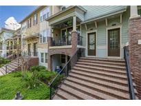 Multi-unit townhouse with a brick staircase leading to covered porches and well-manicured landscaping at 840 Luarca Ln, Oviedo, FL 32765