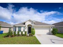 Charming single-story home with a well-kept lawn, two-car garage, and manicured landscaping at 1061 Citrus Landings Blvd, Davenport, FL 33837
