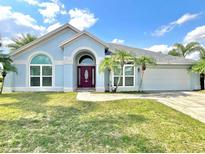 Charming single-story home with a well-manicured lawn, palm trees, and an arched entryway at 12450 Greco Dr, Orlando, FL 32824