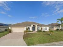 Charming single-story home with a well-maintained lawn, brick driveway, and two-car garage at 152 Moscato Dr, Davenport, FL 33897