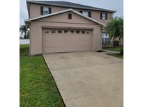 Exterior view of the two-car garage with a long concrete driveway and well-manicured lawn at 4710 Willoughby St, Kissimmee, FL 34758