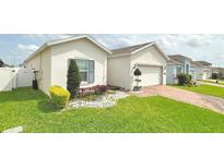 Charming single-Gathering home with manicured lawn, colorful landscaping, and brick paved driveway at 486 Disa Dr, Davenport, FL 33837