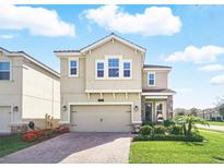 Two-story home boasts a paver driveway, two-car garage, and well-manicured lawn at 1107 Trappers Trail Loop, Davenport, FL 33896
