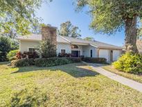 Charming single-story home featuring an attached two-car garage, brick chimney, and beautifully landscaped front yard at 1444 Pelican Bay Trl, Winter Park, FL 32792
