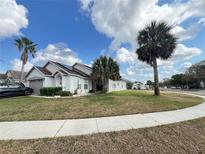 Charming single-story home with palm trees and a well-manicured lawn under a bright blue sky at 2678 Autumn Creek Cir, Kissimmee, FL 34747