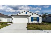 Charming single-Gathering home with a two-car garage, neat landscaping, and vibrant blue shutters at 381 Singing Sands Cir, Lake Wales, FL 33859