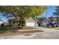 Charming one-story home featuring an attached garage and a cozy front porch with mature landscaping at 4419 Great Harbor Ln, Kissimmee, FL 34746