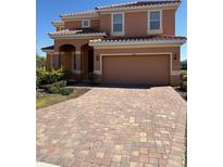 Inviting two-story home featuring a tile roof, arched entry, and paver driveway at 4441 Shiva Loop, Kissimmee, FL 34746