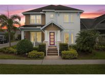 Charming two-story home with landscaped yard, colorful pink entry door, and covered porch at 13831 Briand Ave, Orlando, FL 32827