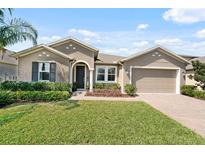 Charming single-story home with manicured lawn, lush landscaping, and brick-paved driveway at 1723 Lake Sims Pkwy, Ocoee, FL 34761