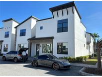 Modern townhome featuring a white exterior, dark trim, and a sleek sports car parked in front at 231 Villa Domani Cir # 59, Davenport, FL 33896