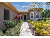 Inviting front entrance with brick paver walkway, colorful landscaping, and a covered doorway into the home at 531 Barcelona Dr, Poinciana, FL 34759