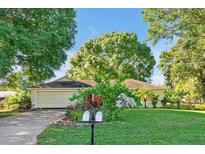 Charming home with a well-manicured lawn, lush greenery, and a two-car garage under a clear, sunny sky at 541 Rebecca Dr, St Cloud, FL 34769