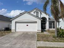 Charming home featuring an attached two-car garage, well-maintained lawn, and mature palm tree at 642 Riggs Cir, Davenport, FL 33897