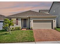 Charming single-story home featuring a neutral color scheme, a two-car garage, and a brick paver driveway at 709 Blackstone St, Minneola, FL 34715