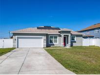 Charming single-Gathering home features a gray exterior, solar panels, a two-car garage, and a well-manicured lawn at 152 Big Black Dr, Kissimmee, FL 34759