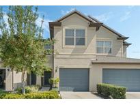 Charming two-story townhome featuring a well-maintained lawn, landscaping, and an attached two-car garage at 10871 Corsican St # 21, Orlando, FL 32824