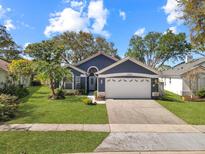 Charming single-story home with a manicured lawn and mature landscaping, painted in pleasing, modern colors at 13223 Meadowlark Ln, Orlando, FL 32828