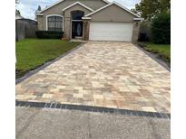 Charming home featuring a brick driveway with an attached garage and a well-maintained front lawn at 205 Lexingdale Dr, Orlando, FL 32828