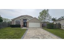Charming single-story home boasts a lovely brick and neutral stucco facade and paver driveway at 205 Lexingdale Dr, Orlando, FL 32828