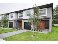 Modern townhome featuring a two-story design, a dark two-car garage, and gray and white color scheme at 4417 Le Reve Ct, Kissimmee, FL 34746