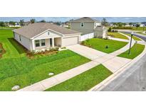 Well-manicured front yard with a lush lawn and a two car garage at 64 Citrine Loop, Kissimmee, FL 34758