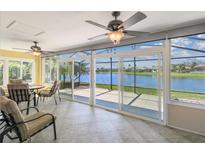 Bright sunroom with tile floors, ceiling fans, and sliding glass doors overlooking a serene lake view at 782 Vineyard Way, Poinciana, FL 34759