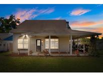 Charming one-story home with a covered porch, lush lawn, and beautiful landscaping at dusk at 2566 Conway Gardens Rd, Orlando, FL 32806