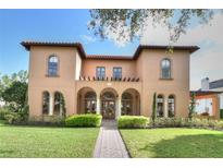 Stunning two-story Mediterranean style home with arched entryway, lush landscaping and a brick walkway at 304 Acadia Ln, Celebration, FL 34747