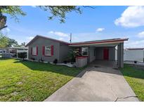 Charming gray single-story home with red trim and an attached carport on a sunny day at 4548 Cepeda St, Orlando, FL 32811