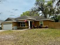 Charming single-story home featuring a well-manicured lawn and an American flag at 74 N Oak Ave, Umatilla, FL 32784