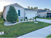 Well-maintained lawn and landscaping enhance the curb appeal of this charming single-story home at 1153 Augustus Dr, Davenport, FL 33896