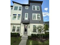 Modern three-story townhome featuring a two-tone exterior and well-manicured landscaping at 12673 Yoshino Aly, Orlando, FL 32827