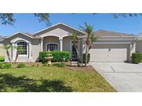 Charming single-story home featuring a well-manicured lawn, lush shrubbery, and a two-car garage at 213 Strathmore Cir, Kissimmee, FL 34744