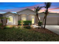 Inviting home featuring a well-manicured lawn, fountain, lush shrubbery and charming curb appeal at dusk at 213 Strathmore Cir, Kissimmee, FL 34744