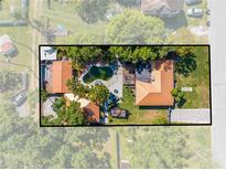 Aerial view of a home with pool, lush landscaping, and unique roof lines surrounded by mature trees and fenced yard at 815 Kentucky Ave, St Cloud, FL 34769